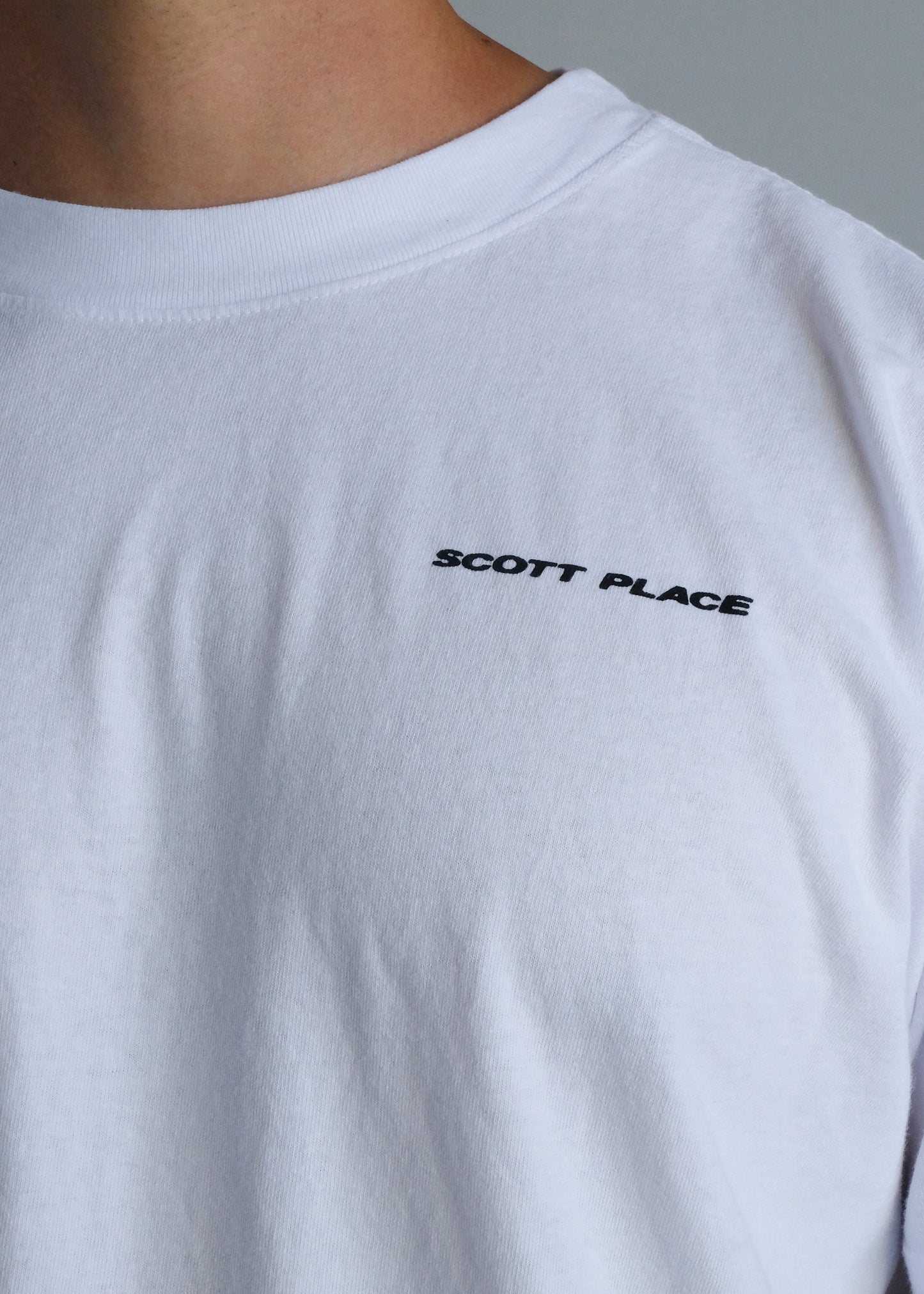 White t-shirt with 'SCOTT PLACE' text on a gray background