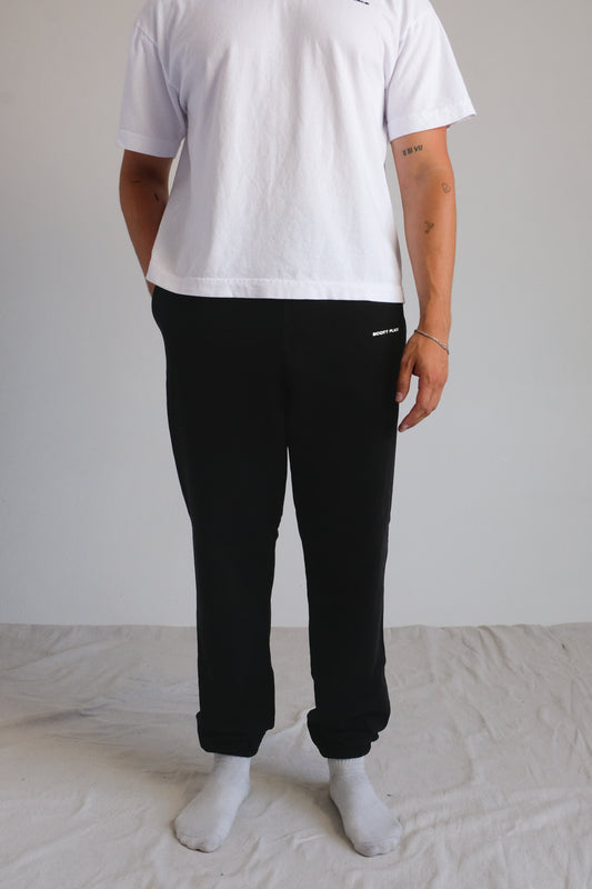 Person wearing a white t-shirt and black pants on a plain background