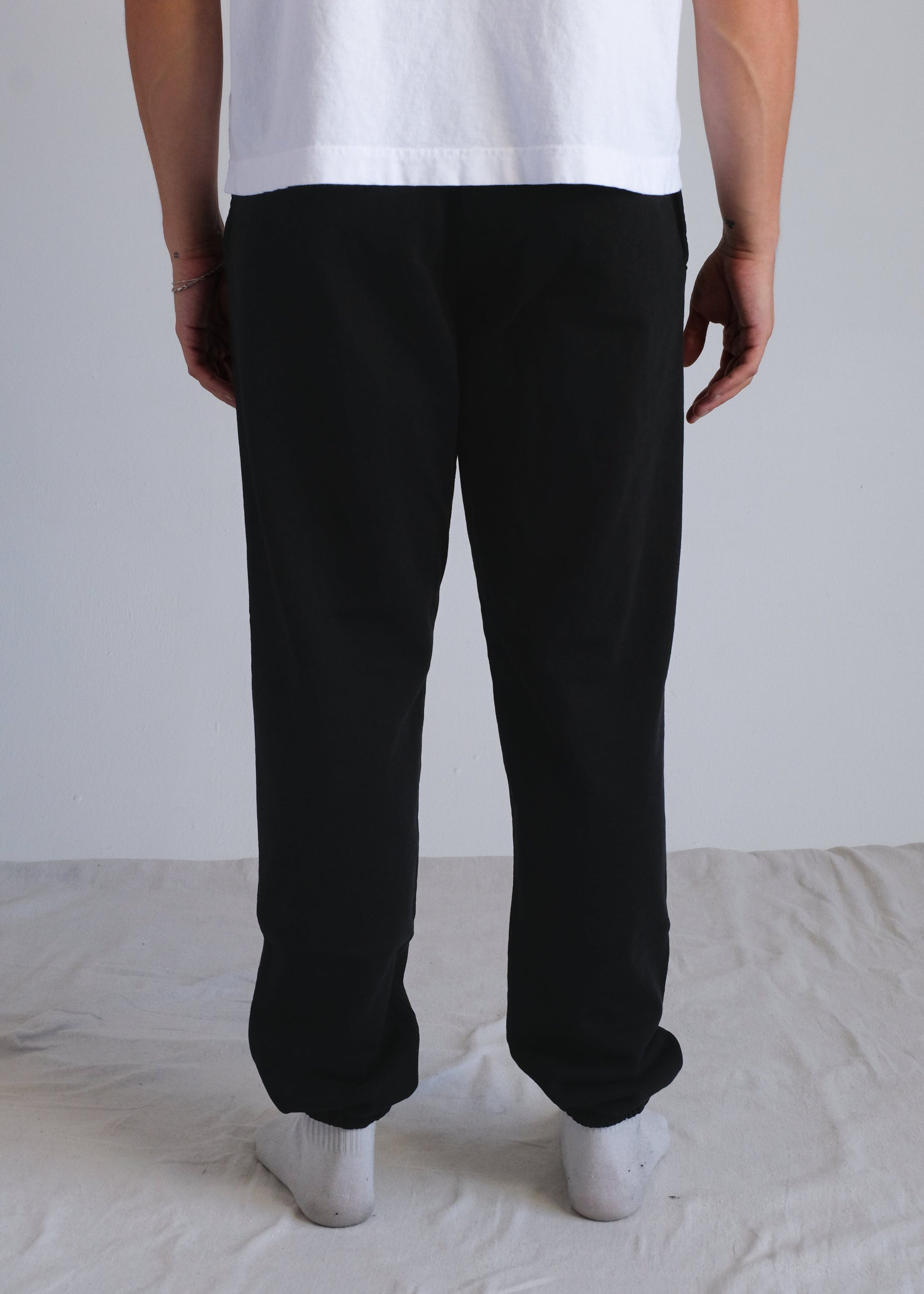 Person wearing black pants and a white shirt on a plain background