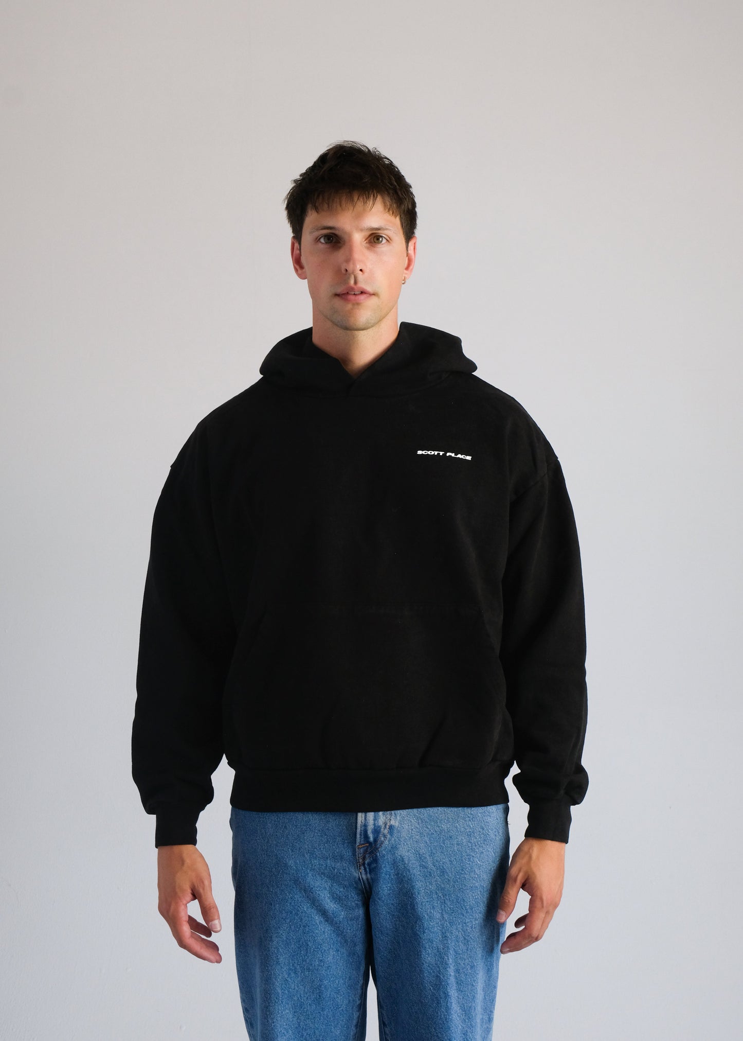 Person wearing a black hoodie with text on a plain background