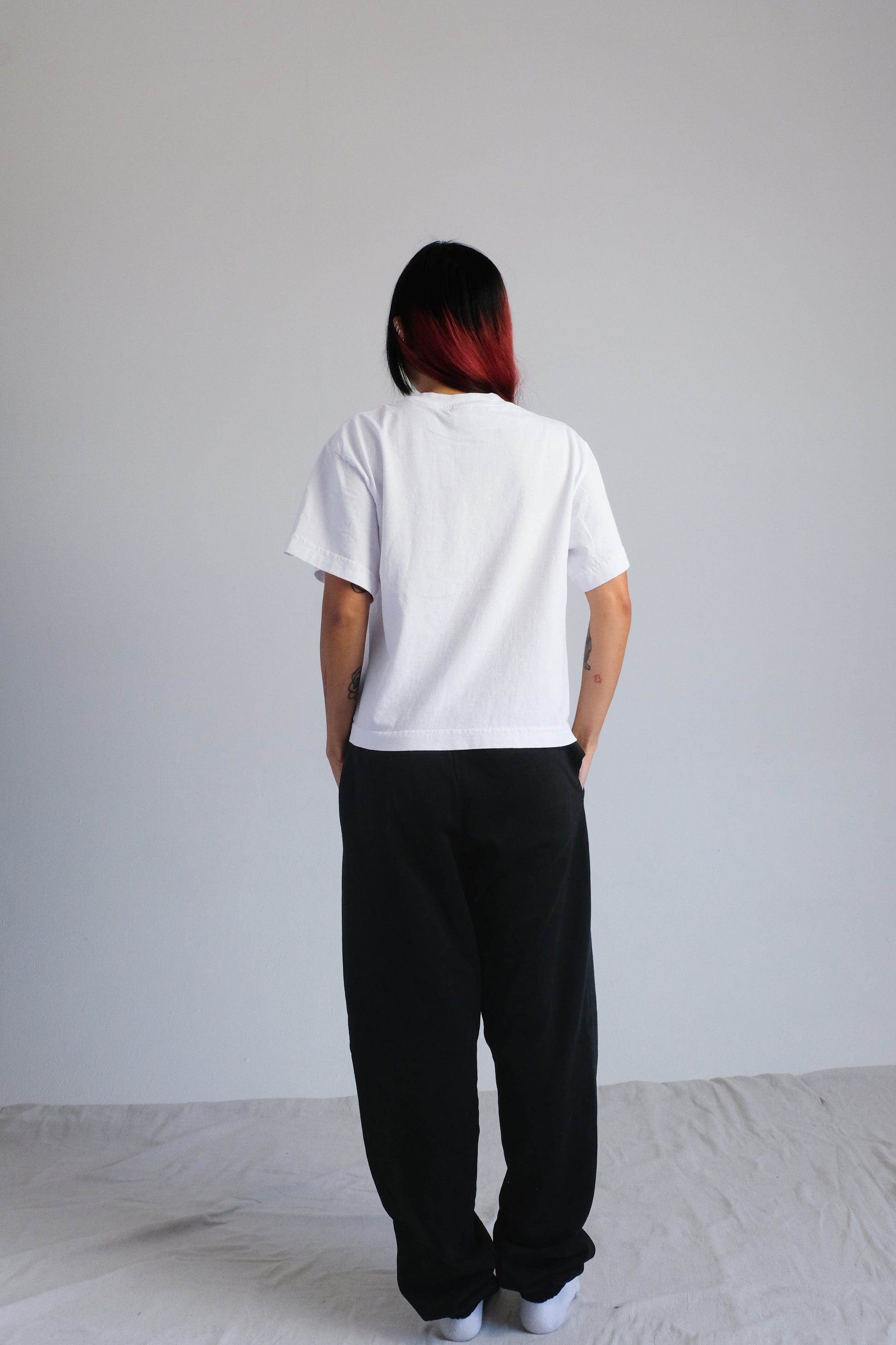 Person wearing a white t-shirt and black pants against a plain background