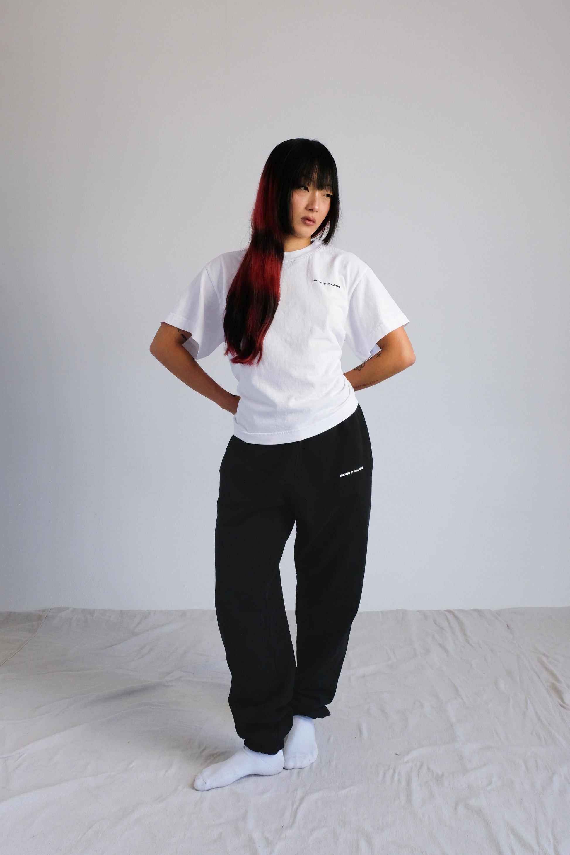 Person wearing a white t-shirt and black pants against a plain background