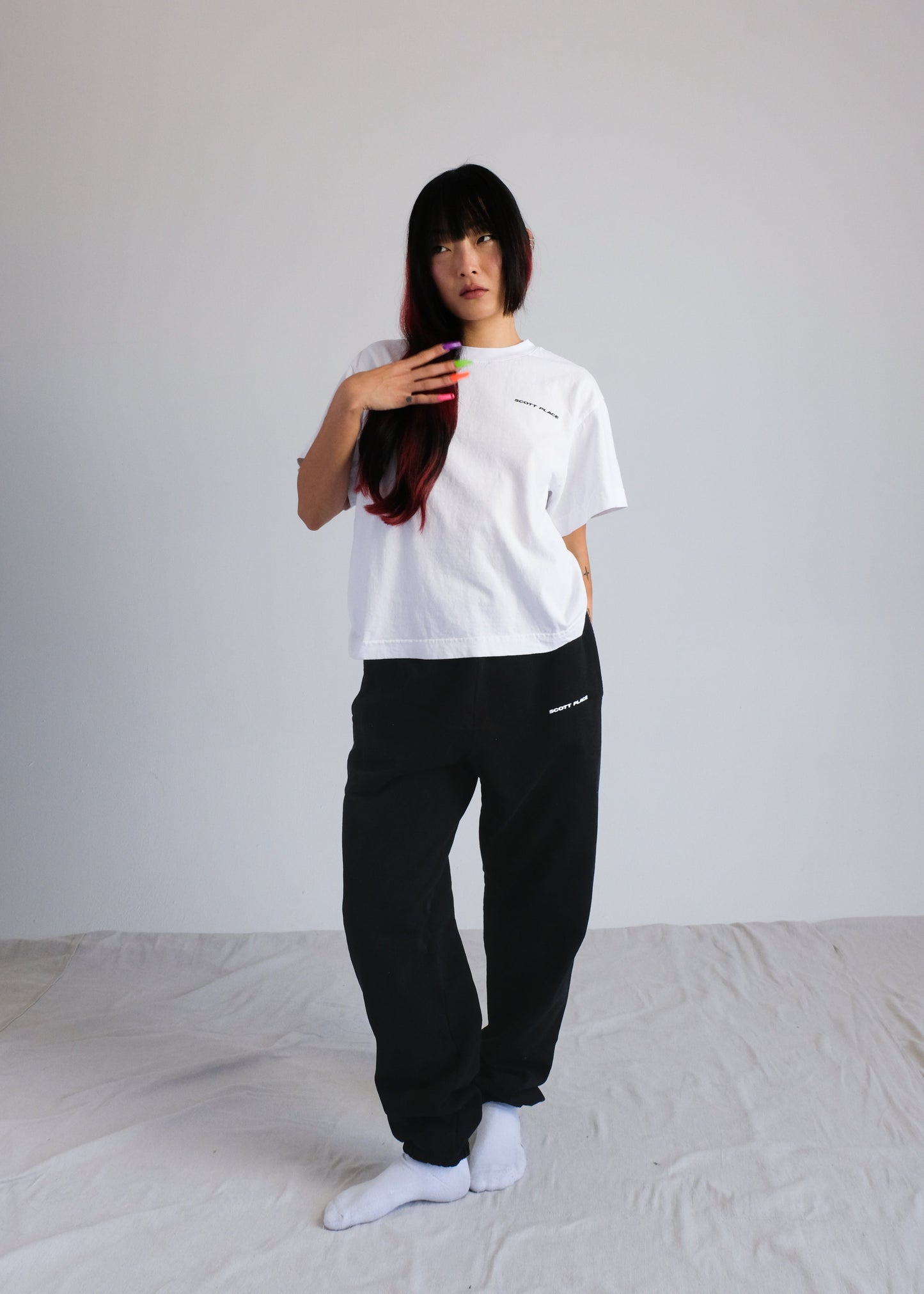 Person wearing a white t-shirt and black pants on a plain background