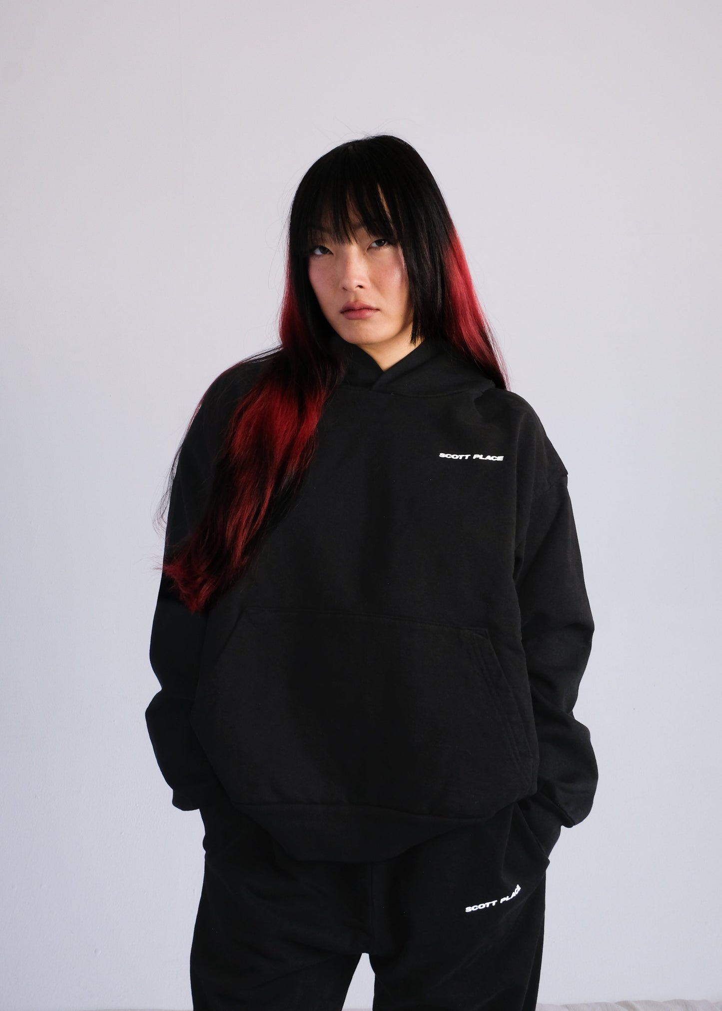 Person wearing a black hoodie with white text on a plain background