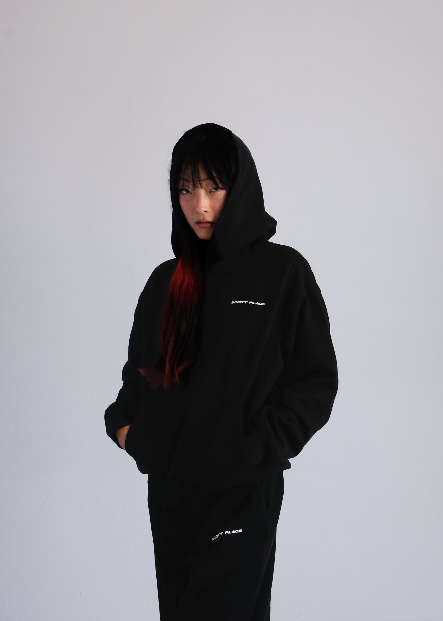 Person wearing a black hoodie with text on a plain background