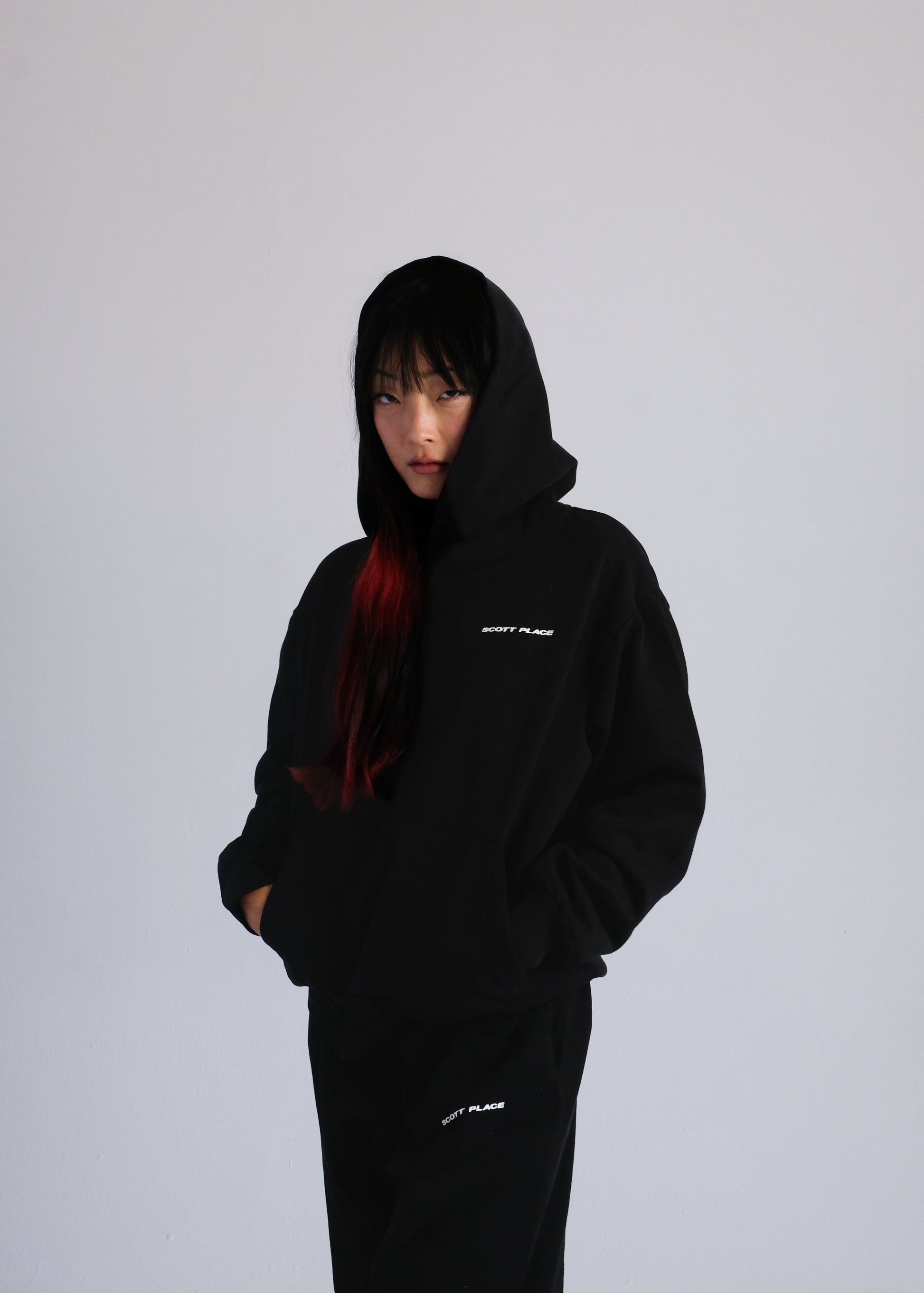 Person wearing a black hoodie with text on a plain background