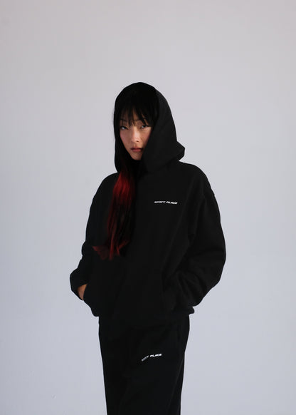 Person wearing a black hoodie with text on a plain background